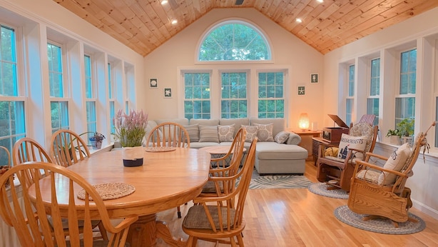 A cozy interior with a wooden dining table, chairs, a sofa, and a fireplace. - 4BD/2BA. Tranquil Cape Getaway for family  (Barnstable)