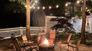 An outdoor patio with a fire pit, chairs, and string lights. - 4BD/2BA. Tranquil Cape Getaway for family  (Barnstable)