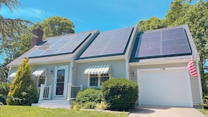 A single-story house with solar panels on the roof, a garage, and a front porch. - 4BD/2BA. Tranquil Cape Getaway for family  (Barnstable)