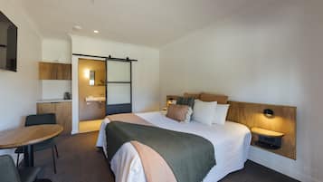 A hotel room with a bed, bedside table, nightstand, and a desk with chairs.