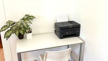 A white desk with a printer, a potted plant, and a framed nautical chart on the wall.