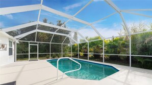 A covered swimming pool with a white roof, surrounded by greenery. - CHARMING FLORIDA GETAWAY 3BDR HOME WITH A POOL (Rotonda West)
