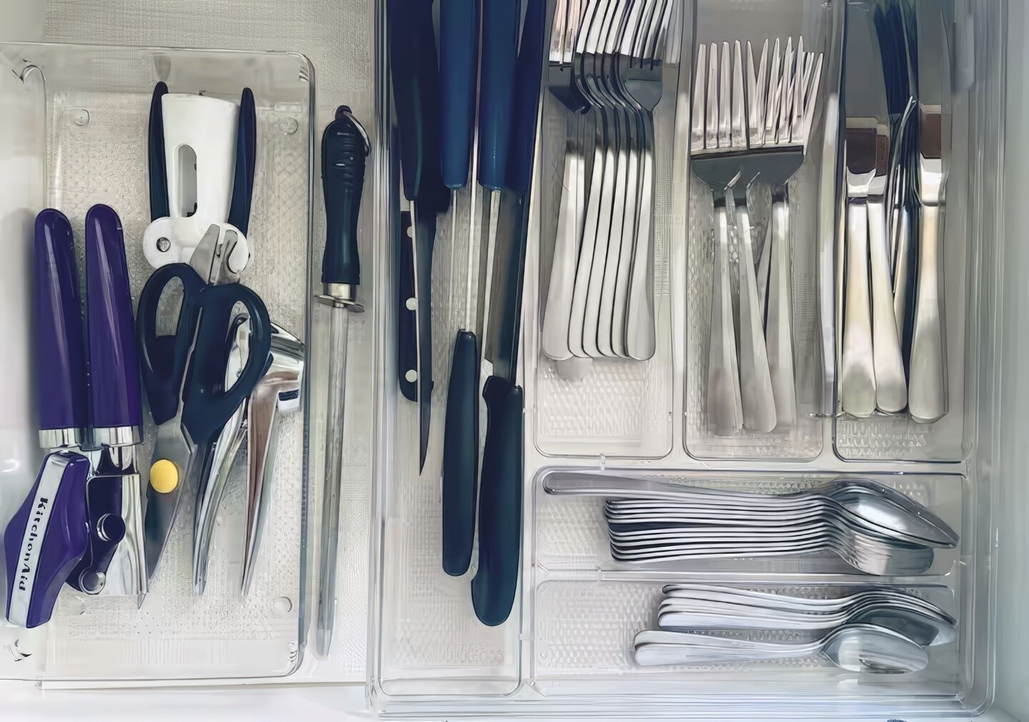 Uma gaveta com diversos utensílios de cozinha organizados em divisórias.