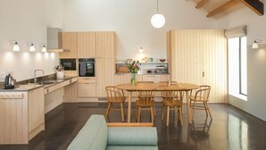 Una cocina moderna con armarios de madera, una isla central y un comedor con una mesa redonda y sillas.
