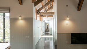 Una cocina moderna con armarios blancos, un comedor con mesa y sillas, y un televisor montado en la pared.