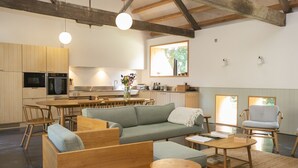 A modern kitchen with wooden cabinets, a dining area with a round table, and a living space with a sofa and chairs. - Lookout -  Lower Wraxall, Cattistock (Dorchester)