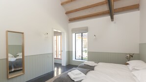 A bedroom with two beds, a large mirror, and a window with blinds. - Lookout -  Lower Wraxall, Cattistock (Dorchester)
