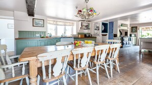 Una cocina espaciosa con una mesa y sillas de madera, un candelabro y vistas al jardín.