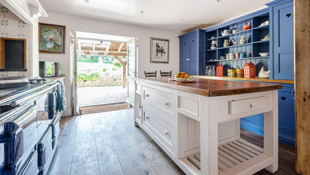 Una cocina con armarios blancos, encimera de madera y vistas al exterior.