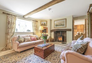 A cozy living room with a fireplace, two sofas, a coffee table, and a patterned rug.
