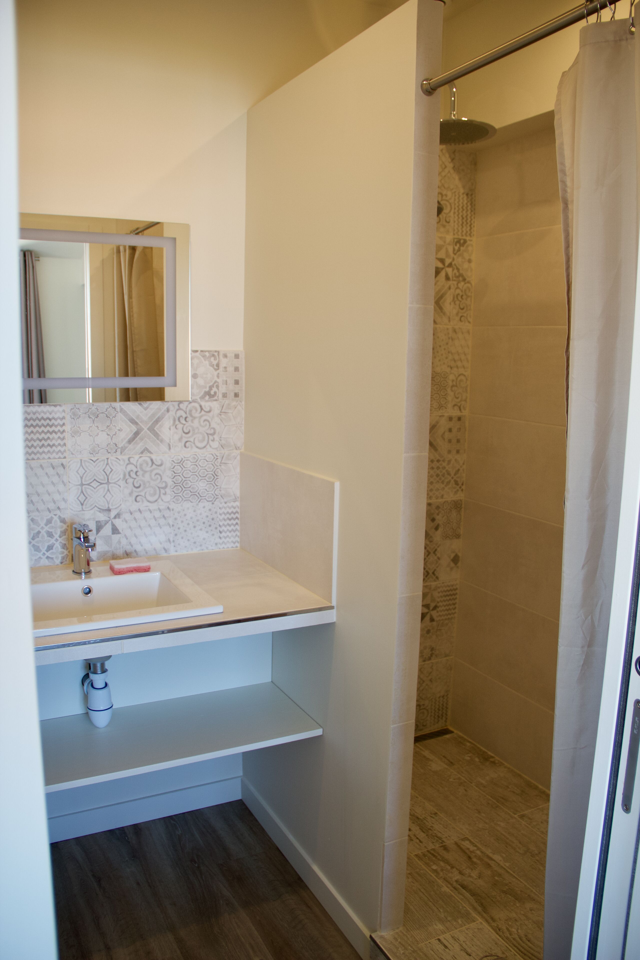 Une salle de bain avec un lavabo blanc, un miroir et des carreaux à motifs.