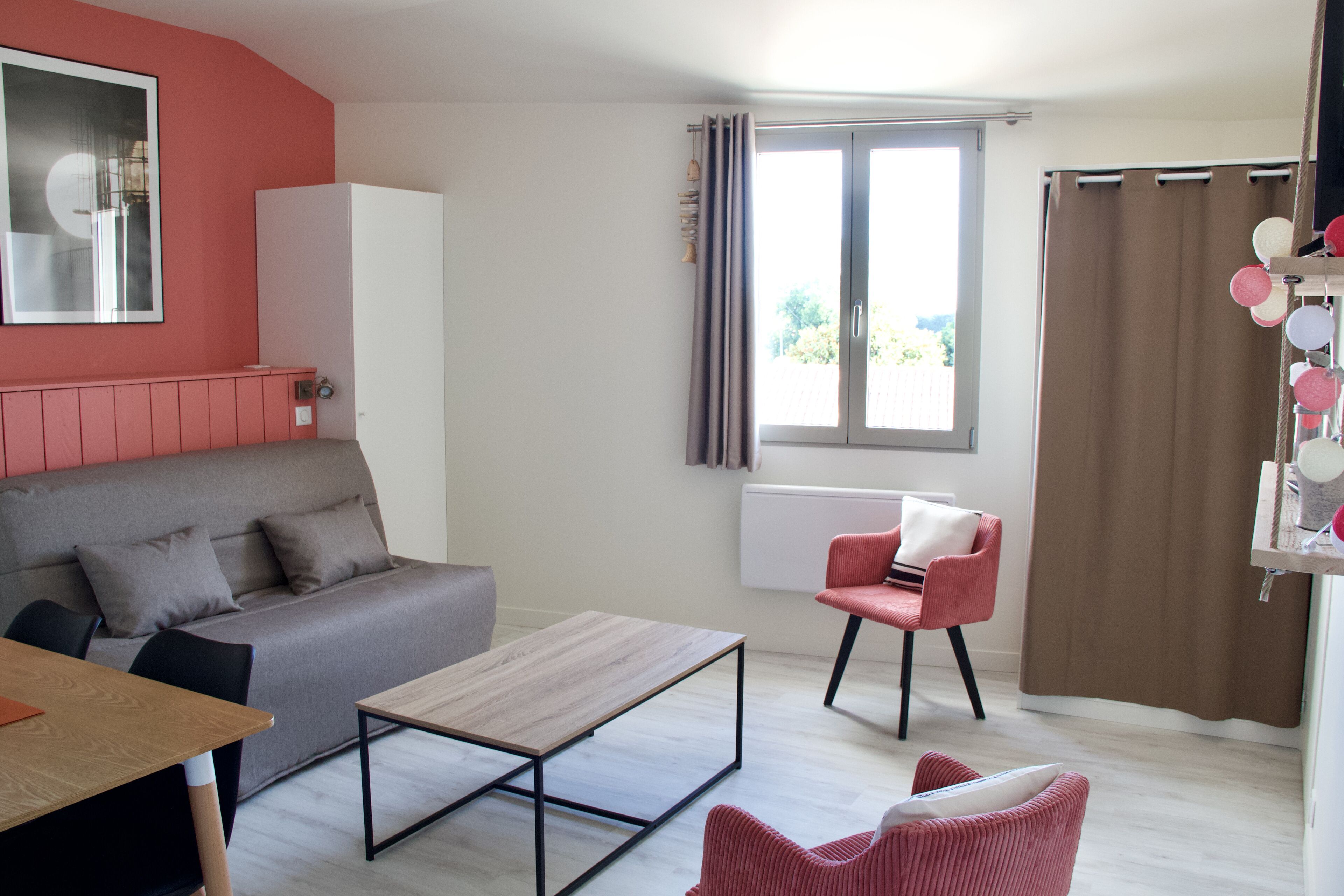 A modern living room with a grey sofa, a wooden coffee table, and a red chair.