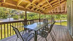Terraza al aire libre techada con mesa y sillas, con vistas a un río y vegetación.