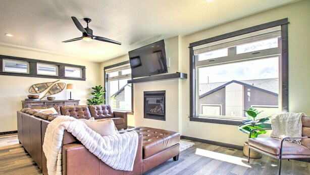 A modern living room with a leather sofa, a flat-screen TV, and a fireplace. - Modern Bozeman Family Townhome w/ Hot Tub! (Bozeman)
