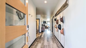 A hallway with wooden flooring, a glass door on the left, and a wall with hats hanging on the right. - Modern Bozeman Family Townhome w/ Hot Tub! (Bozeman)