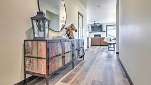 A hallway with a wooden cabinet, a mirror, and a mounted horse sculpture. - Modern Bozeman Family Townhome w/ Hot Tub! (Bozeman)