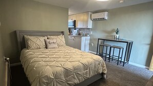 A bedroom with a bed, a small kitchenette, and a ceiling light. - Beautiful Studio Suite #4 (Loa)