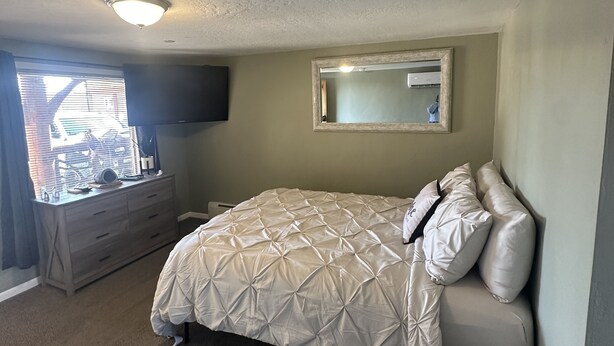 A bedroom with a bed, a dresser, a mirror, and a window with blinds. - Beautiful Studio Suite #4 (Loa)