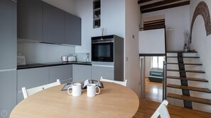 A modern kitchen with grey cabinets, a black microwave, and a dining table with two white mugs. - Italianway - Frisi 8 (Milan)