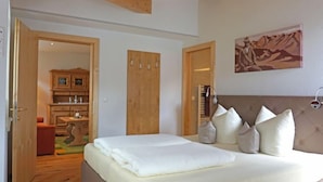 A bedroom with a bed, wooden wardrobe, and a painting on the wall. - Apart B by Interhome (Ried im Oberinntal)