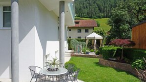 Eine moderne Außenpatio mit einem runden Tisch und Stühlen, umgeben von einem gepflegten Rasen und einem Holzzaun.