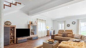 Un salon spacieux équipé d’un téléviseur à écran plat, d’un canapé, d’une table basse et d’un escalier.