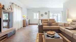 Un salon spacieux avec un canapé d’angle, une table basse et un meuble pour la télévision.