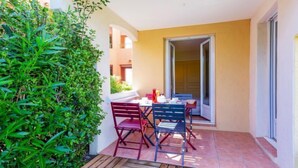 A small patio with a table and chairs, surrounded by greenery and a yellow wall. - Domaine VarAzur by Interhome (Les Issambres)