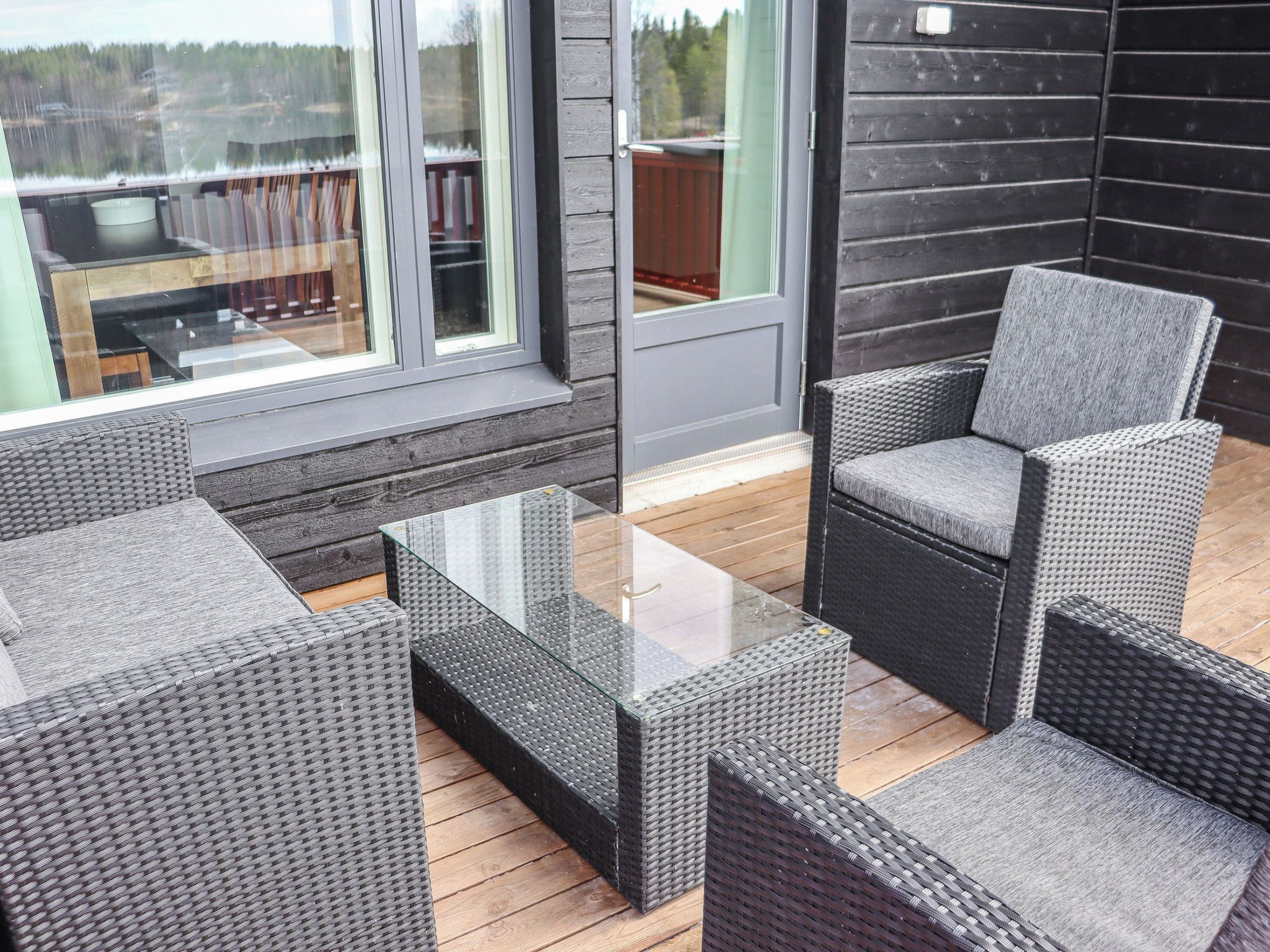 A modern outdoor seating area with wicker furniture and a glass-top table.