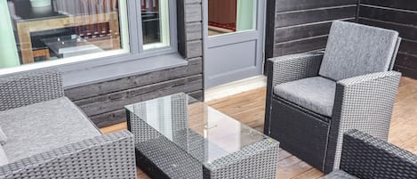 Een moderne buitenruimte met rieten meubels en een tafel met glazen blad.