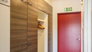 Un corridoio con un armadio in legno, una porta rossa e un cartello di uscita di sicurezza.