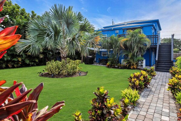 A blue house with a well-maintained lawn and a paved pathway.