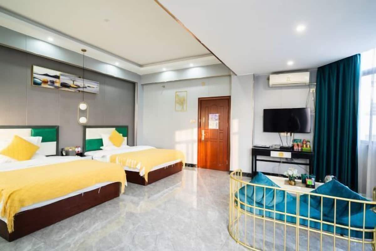 Une chambre d’hôtel avec deux lits, une télévision, un bureau et une fenêtre avec des rideaux.