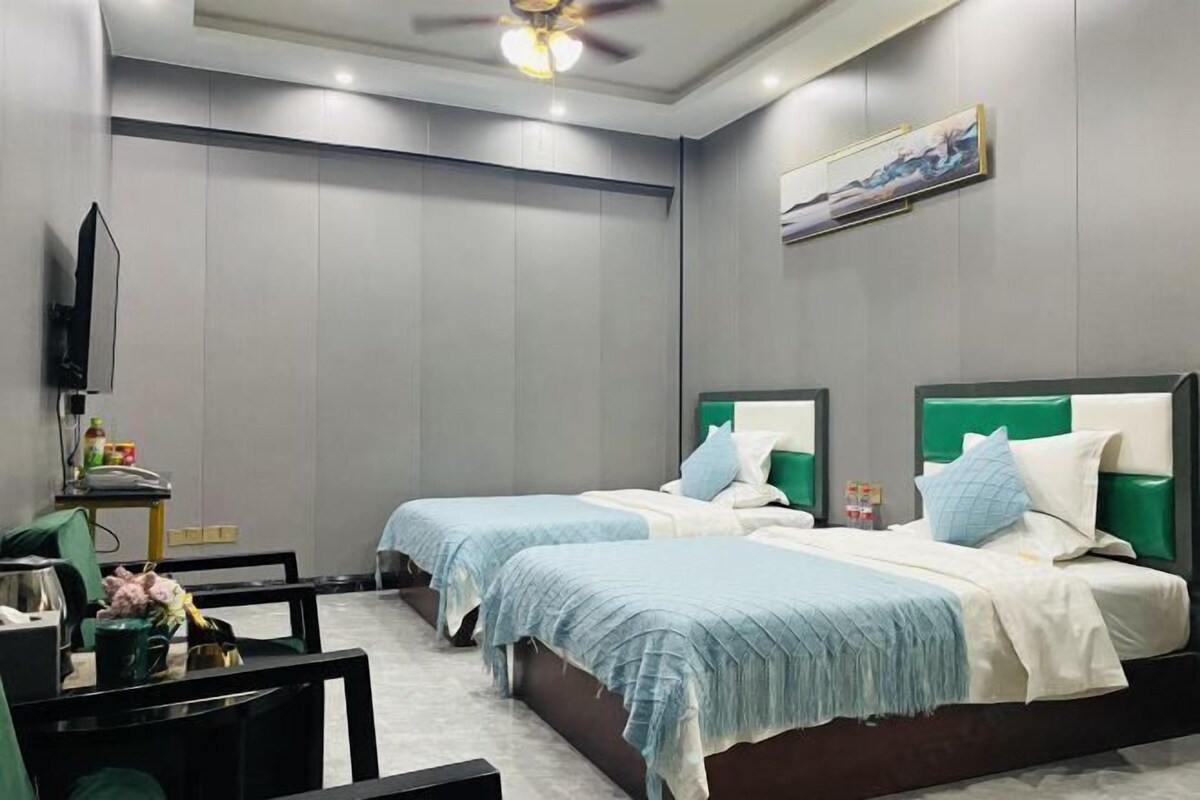 A hotel room with two beds, a TV, and a painting on the wall.
