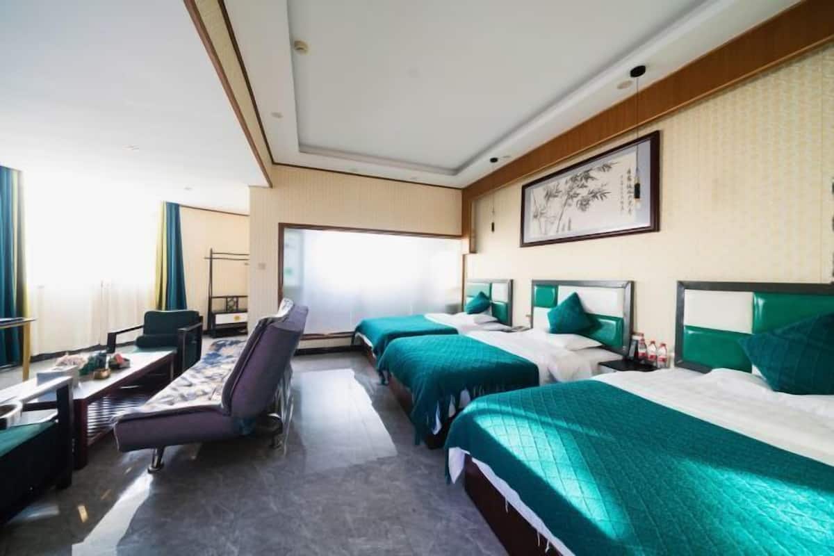 Une chambre d’hôtel avec trois lits, un bureau et une chaise.