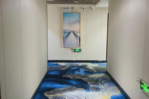 A hallway with a floor design depicting waves and a painting on the wall.