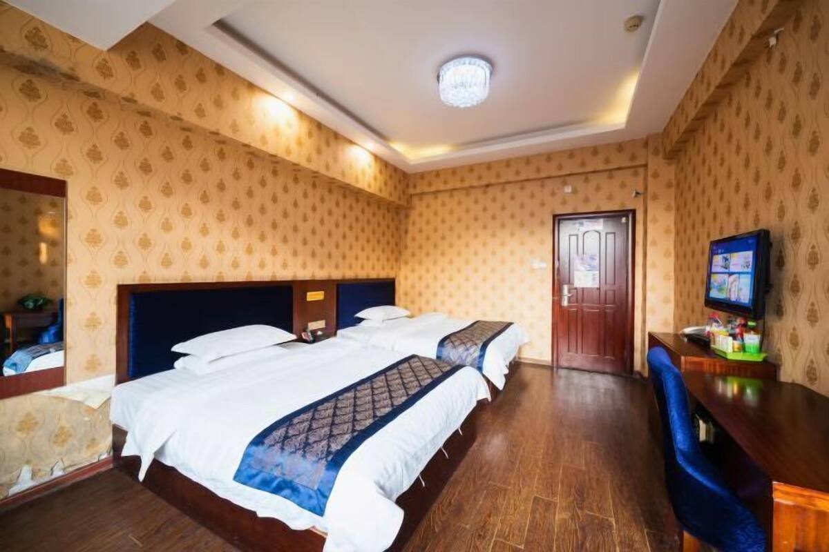 Une chambre d’hôtel avec deux lits, un bureau, une télévision et une porte.