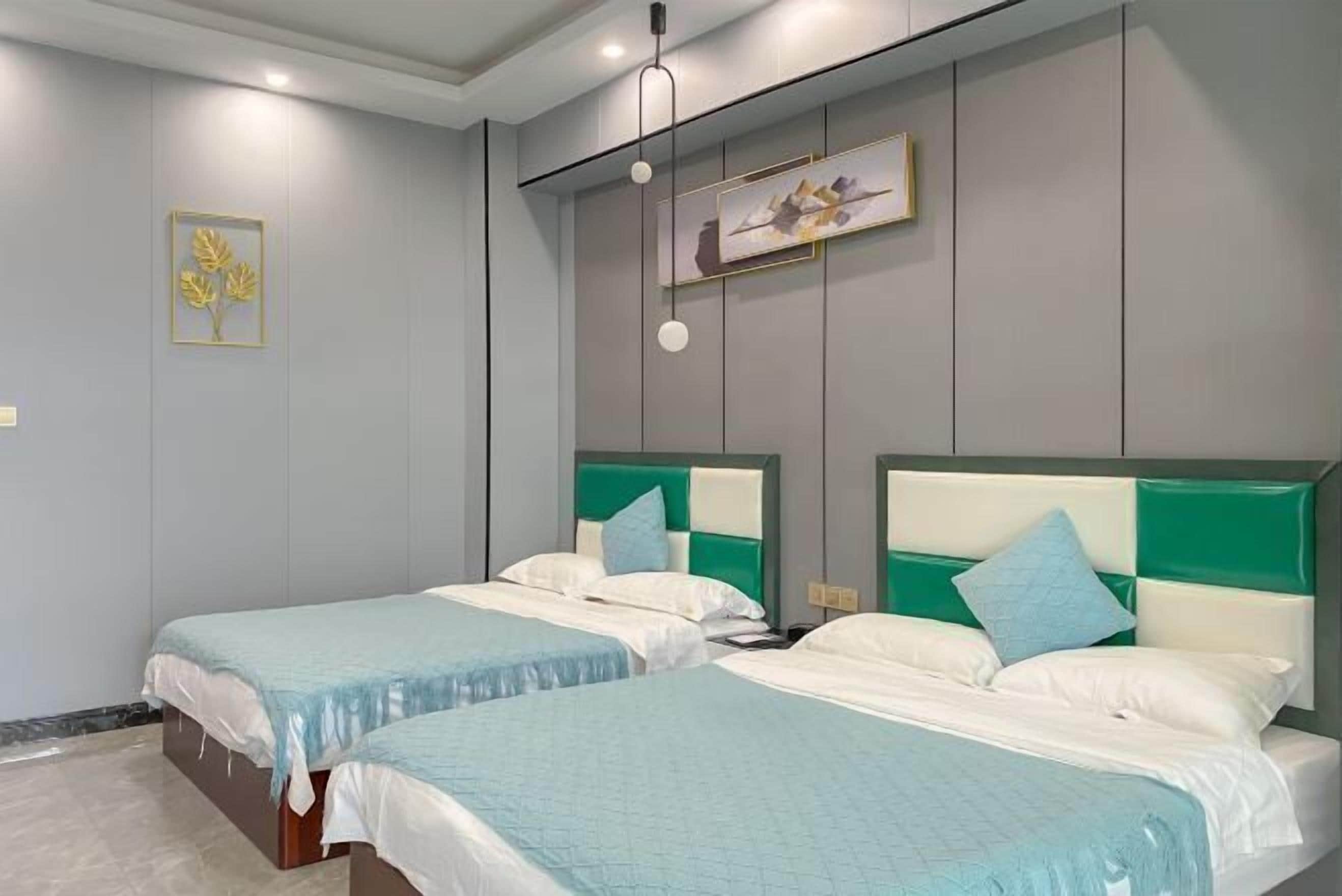 Une chambre d’hôtel avec deux lits, un mur gris et une œuvre d’art encadrée.