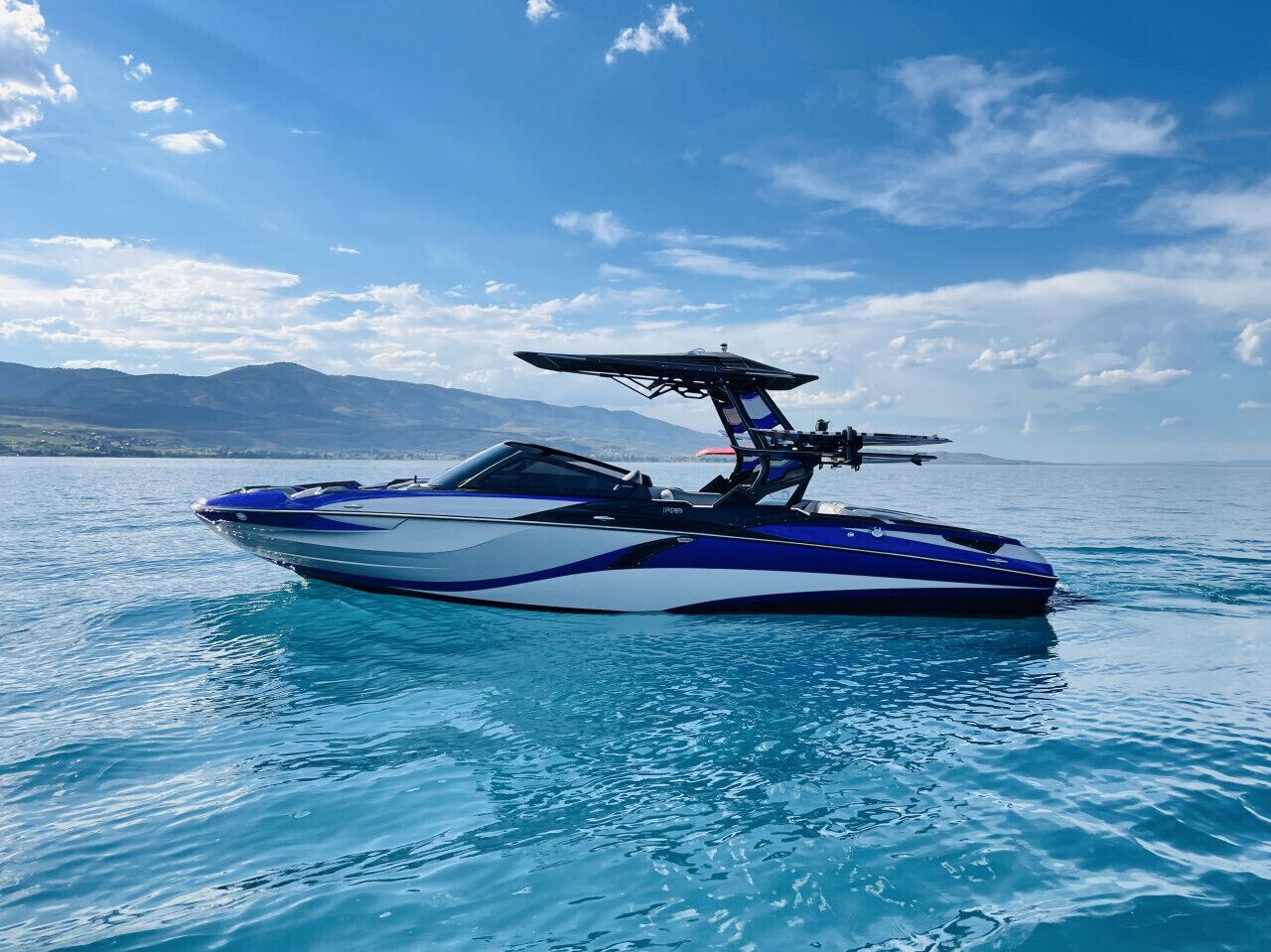 Un velero en un cuerpo de agua con montañas al fondo.