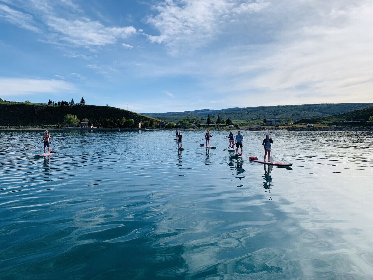 Peaceful paddleboarding on crystal-clear waters, surrounded by scenic hills and open skies—pure serenity.