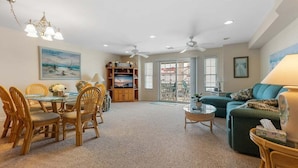 A spacious living room with a dining area, a sofa, and a TV. - 3 Br Condo w/ Ocean Views, Only Steps from Beach! (North Wildwood)