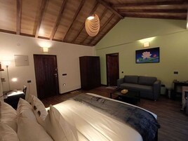 Um quarto com uma cama, um sofá, uma escrivaninha e uma pintura de flores de lótus.