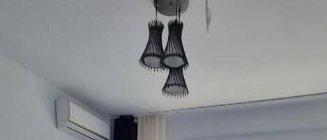 Un dormitorio con cama, suelo de madera, lámpara en el techo y vistas a través de una ventana.