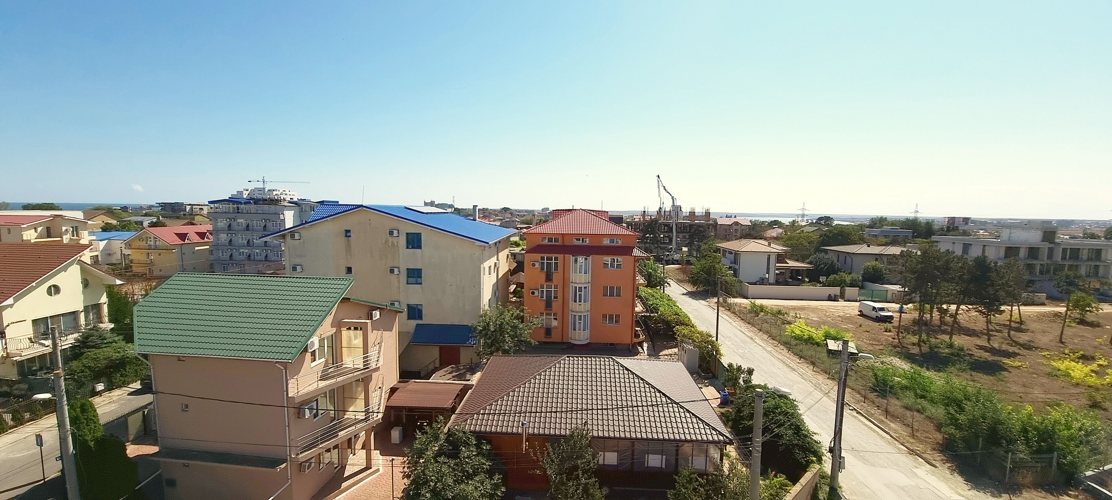 A residential area with multi-story buildings, a street, and a crane in the distance.