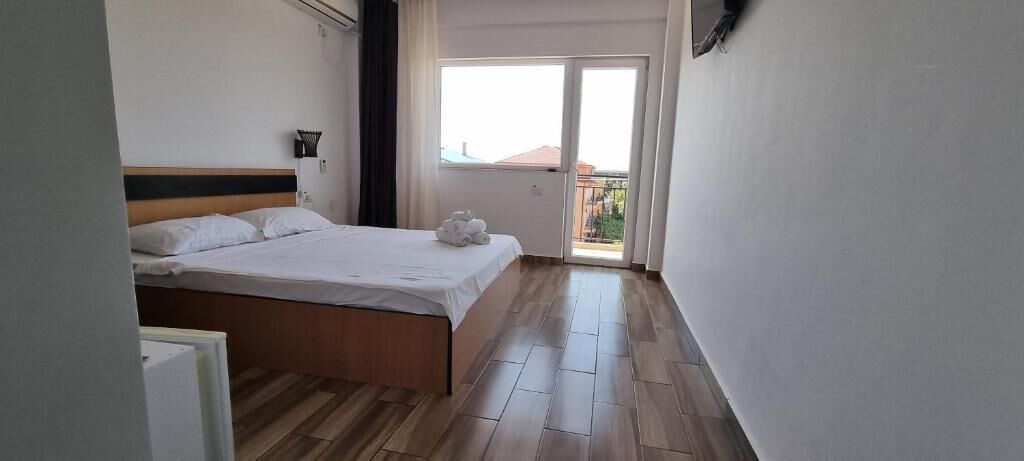 A bedroom with a bed, a nightstand, a window, and a balcony.