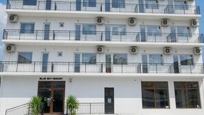 Un hotel de varios pisos con balcones, unidades de aire acondicionado y un cielo despejado.