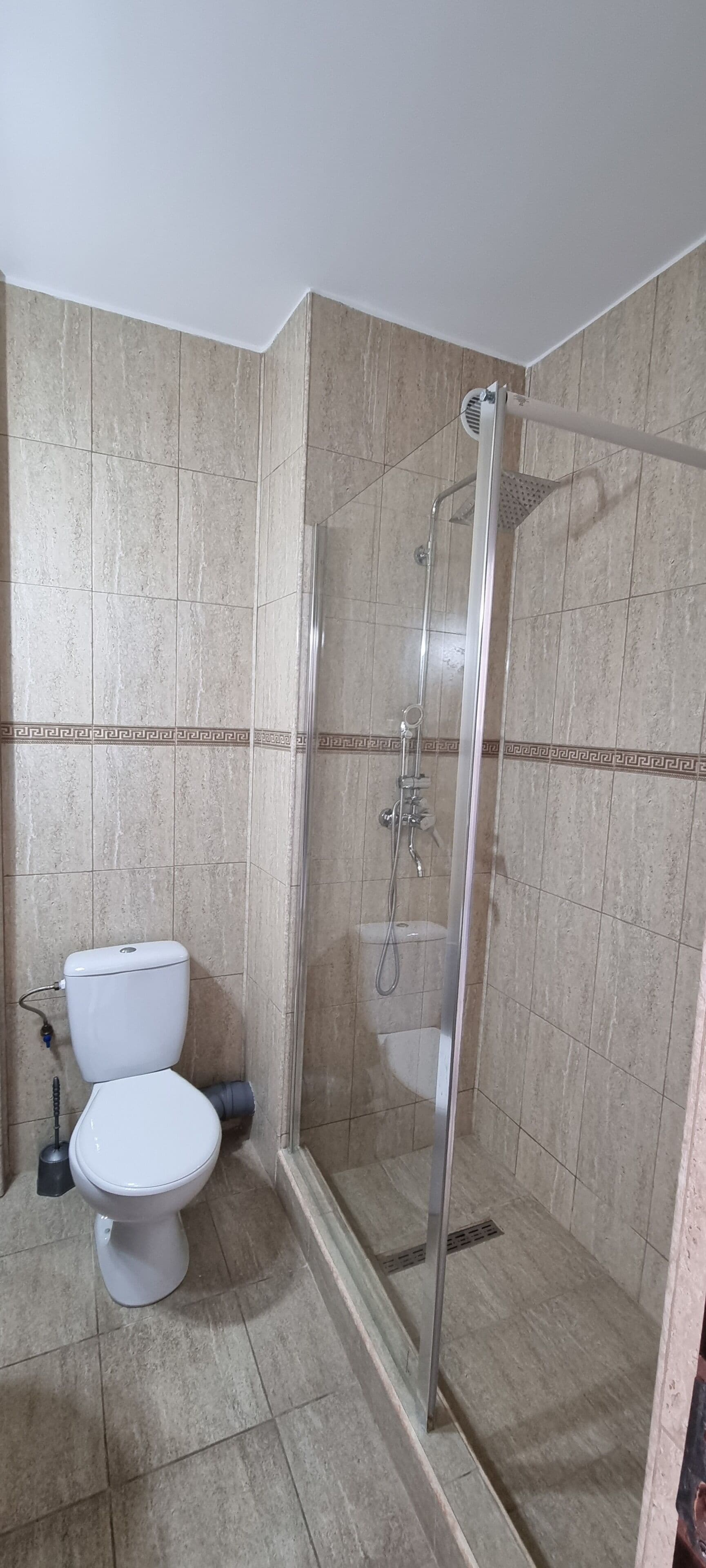 A bathroom with a toilet, shower, and tiled walls.