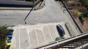 Vista aérea de un estacionamiento con varios autos y un contenedor verde.