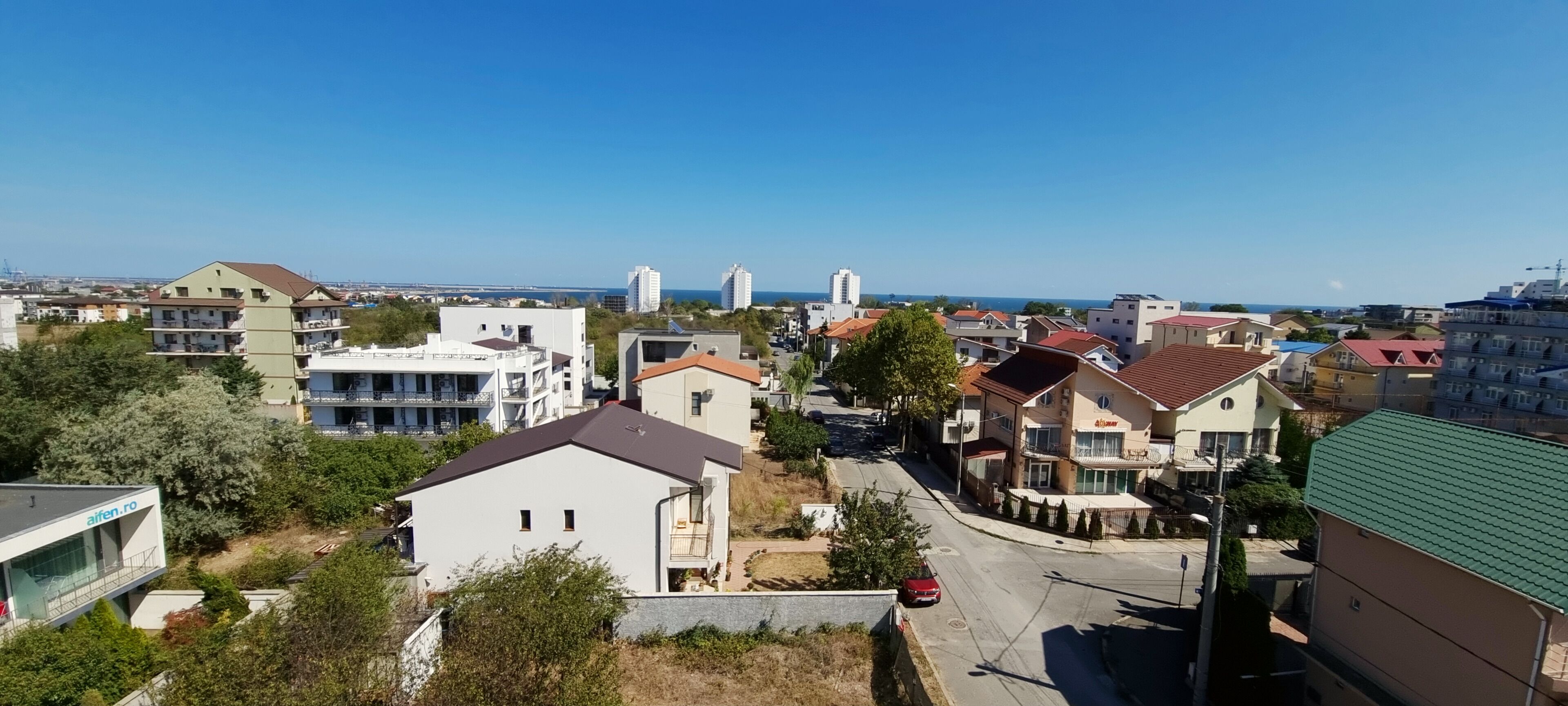 Un quartier résidentiel où l’on trouve différents types de bâtiments, notamment un appartement moderne doté d’un balcon et une maison traditionnelle avec un toit rouge.