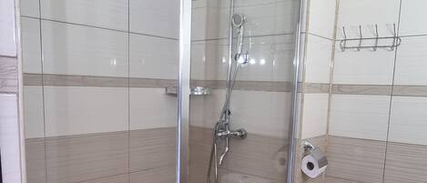 Un baño con ducha de vidrio, inodoro y toallero.